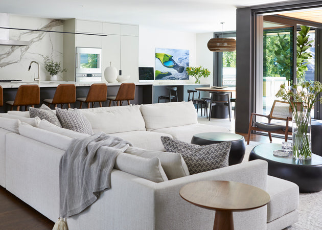 Open concept living room and kitchen with L-shaped sofa and monochromatic stylings