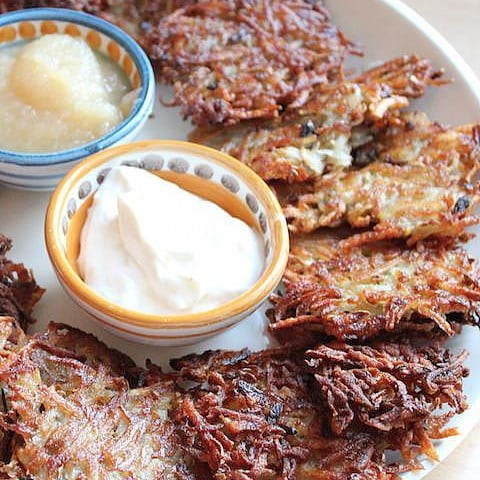 Hanukkah Latkes on a plate with various dipping sauces.